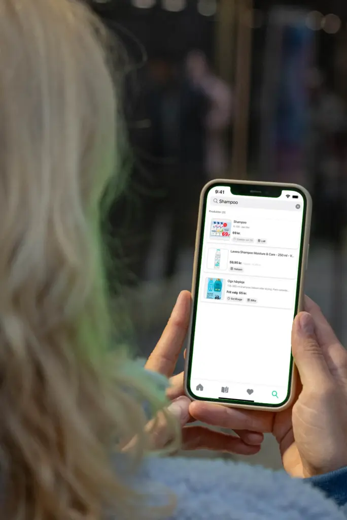 Bruger der holder smartphone med MineTilbud-app og søger efter shampoo i tilbud