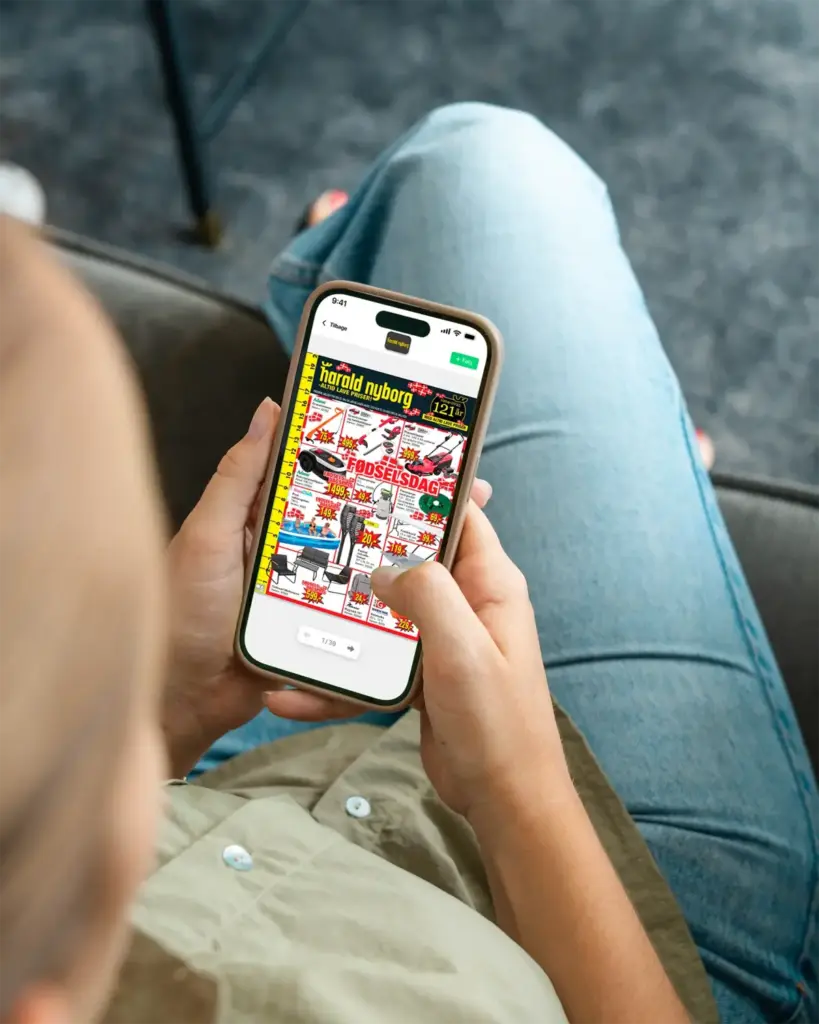 Person der holder smartphone og læser Harald Nyborg tilbudsavis i MineTilbud-app